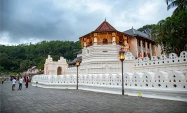 Front view of the Temple of the Tooth Relic in Kandy, Sri Lanka, under a bright blue sky.
