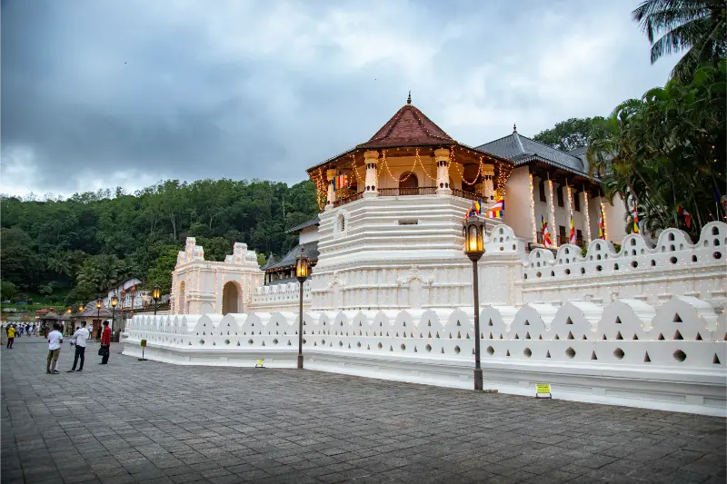 Front view of the Temple of the Tooth Relic in Kandy, Sri Lanka, under a bright blue sky.