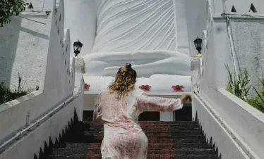 Tourist climbing steps towards the giant Bahirawakanda Buddha Statue in Kandy, Sri Lanka, on a sunny day.